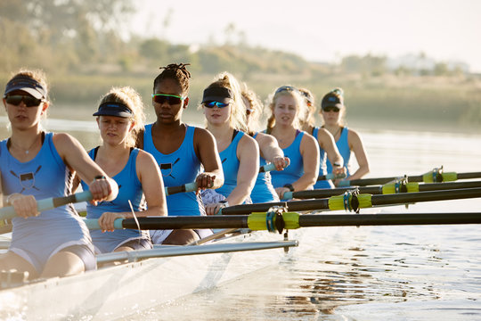 Female rowers rowing scull on sunny lake