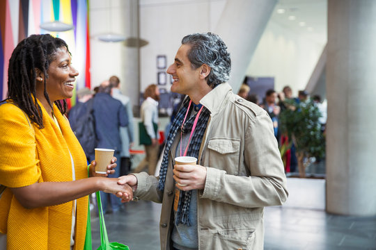 Businessman and businesswoman networking, handshaking at conference