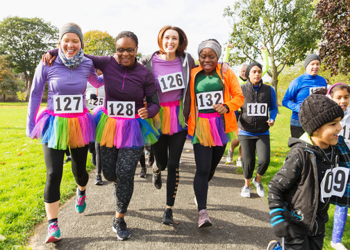 Smiling female runners in tutus walking at charity run in park