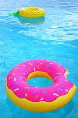 A pink plastic pool float shaped like a donut with sprinkles