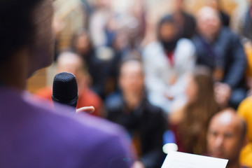 Businessman with microphone speaking to conference audience