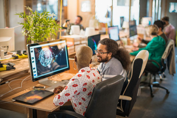 Designers meeting, working at computer in open plan office