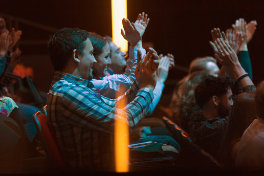 Audience clapping in dark room