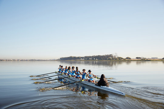 Female rowing team rowing scull on tranquil lake