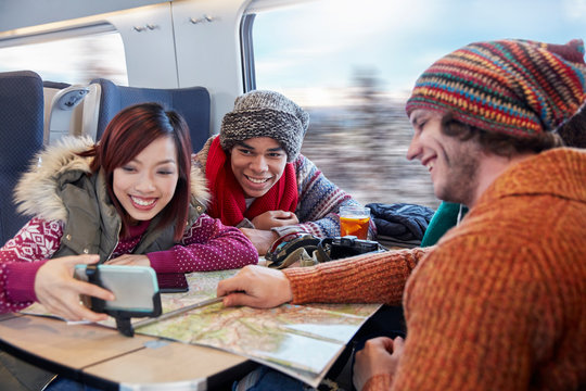Young friends map taking selfie selfie stick on passenger train