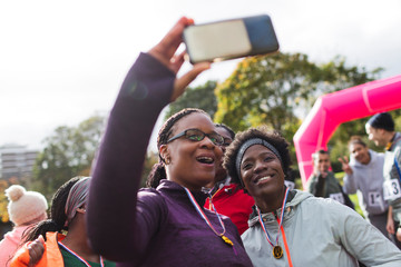 Female runner friends taking selfie at charity run in park