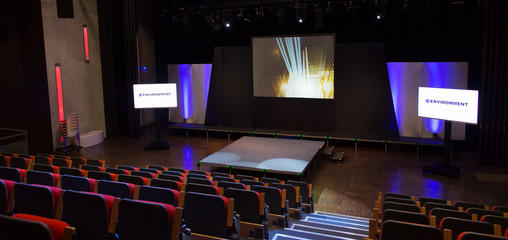 Projection screens and seats in empty conference auditorium