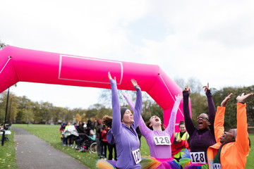 Enthusiastic female runners in tutus cheering, celebrating at charity run finish line