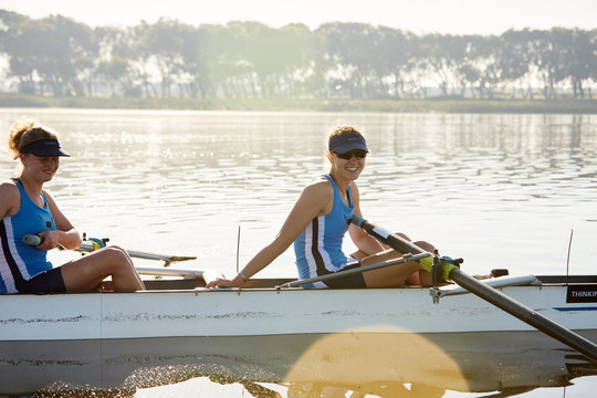 Portrait smiling female rower in scull on sunny lake