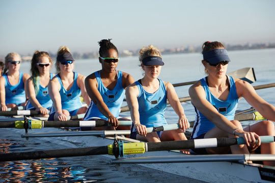 Female rowers rowing scull on sunny lake