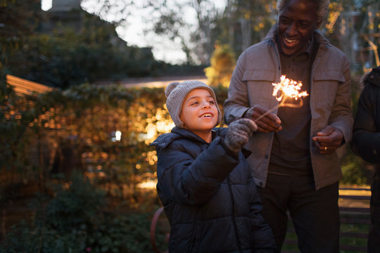 Smiling grandson and grandfather playing with firework sparklers