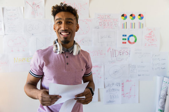 Portrait smiling, confident creative businessman hanging paperwork on office wall