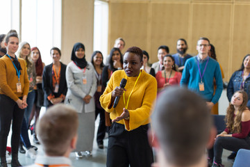 Conference audience listening to businesswoman speaker with microphone