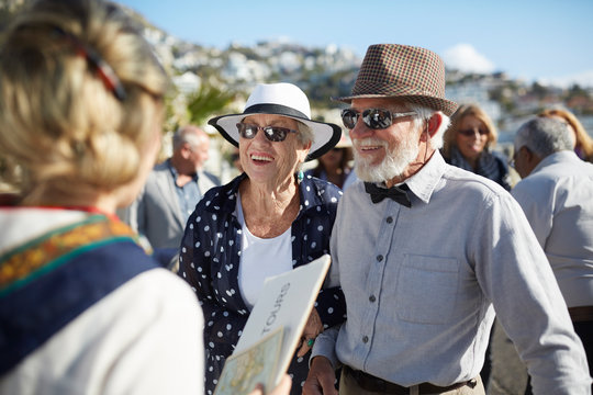 Active senior tourist couple talking with tour guide