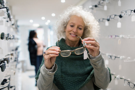 Senior woman shopping for eyeglasses in optometry shop