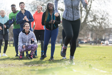 Team cheering woman doing speed ladder drill in sunny park