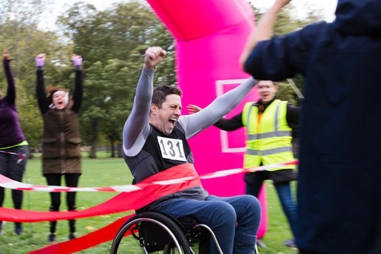 Enthusiastic man in wheelchair crossing charity race finish line