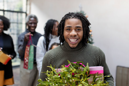 Portrait smiling, enthusiastic young man with Christmas gift mistletoe