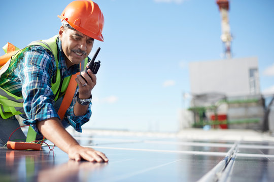 Engineer with walkie-talkie inspecting solar panel at power plant