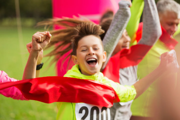 Enthusiastic boy runner crossing charity run finish line