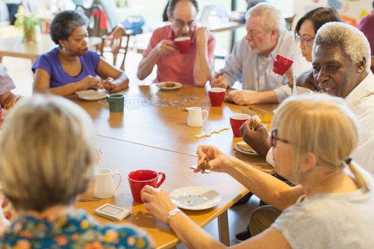 Friends drinking tea and playing games at table in community center