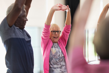 Smiling active seniors exercising, stretching arms
