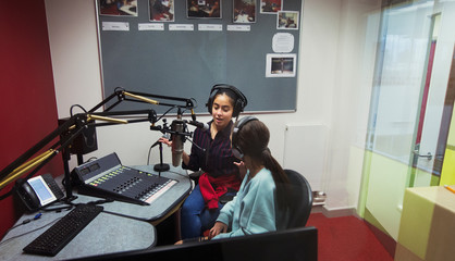 Teenage girl musicians recording music, singing in sound booth