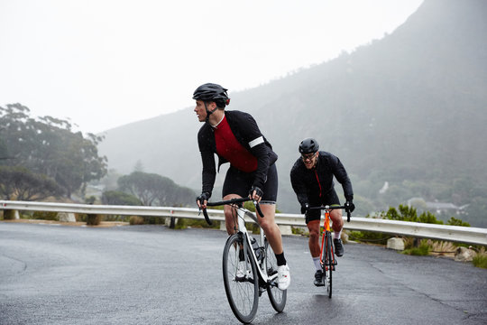 Dedicated Male Cyclists Cycling On Wet Road