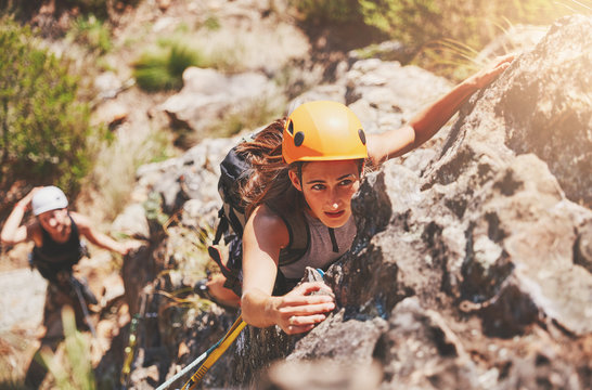 Focused, determined female rock climber hanging from rock