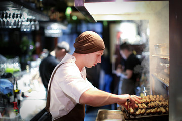 Professional chef preparing grilled sausages in a commercial kitchen/Chef man cooking in the kitchen