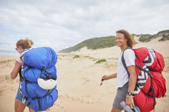 Portrait happy male paraglider with parachute backpack on beach