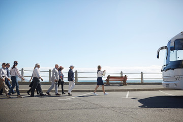 Tour guide leading active senior tourists to tour bus