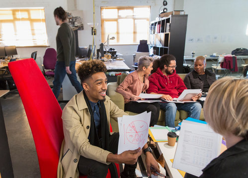Creative business people meeting, discussing paperwork in open plan office