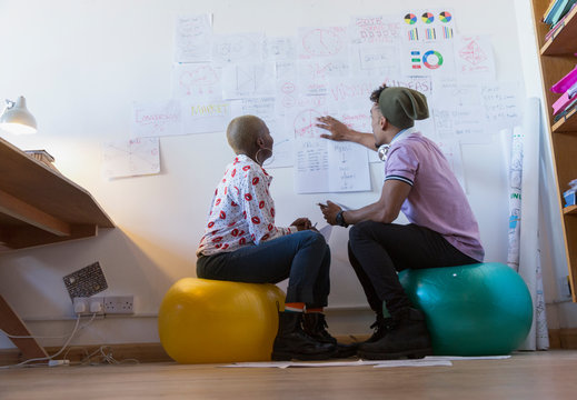 Creative business people on fitness balls meeting, discussing paperwork
