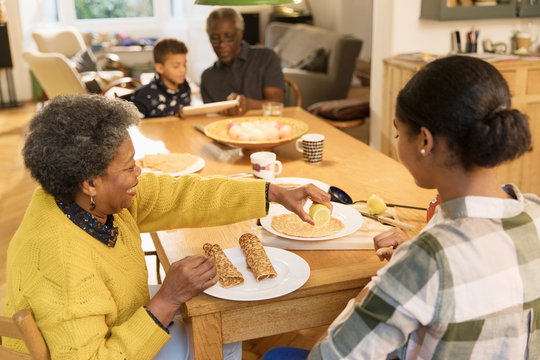 Grandmother and granddaughter eating crepes at dining table - Powered by Adobe