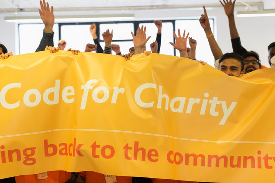 Hackers with banner cheering, coding for charity at hackathon