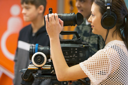 Teenage girl operating video camera, vlogging