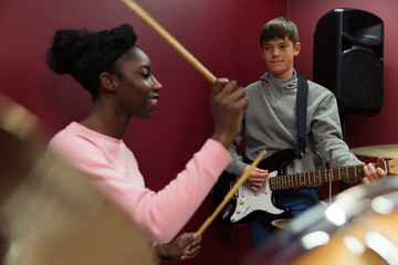 Teenage musicians recording music, playing guitar drums in sound booth
