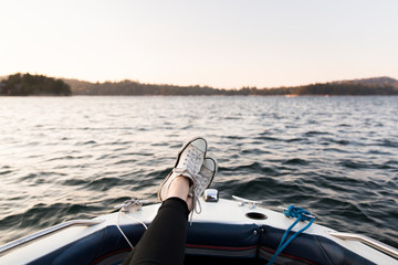 Personal perspective woman boating with feet up on tranquil lake