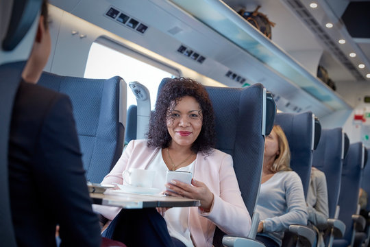 Portrait smiling, confident businesswoman using smart phone on passenger train