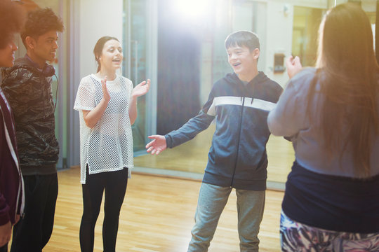 Classmates clapping for teenage boy in dance class studio
