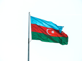 National flag of Azerbaijan flowing during national holiday against clear blue sky - central Baku