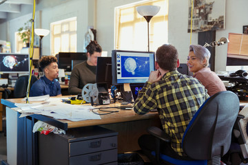 Creative business people working at computers in open plan office