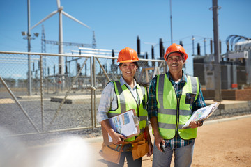 Portrait smiling, confident engineers with clipboards at power plant