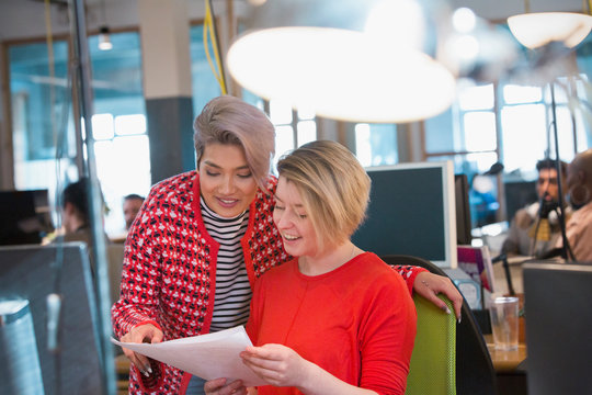 Creative businesswomen discussing paperwork in open plan office