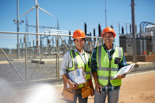 Portrait smiling, confident engineers with clipboards at power plant