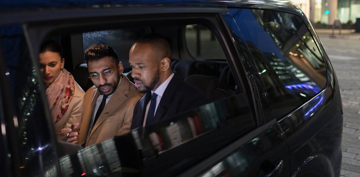 Business people in back seat of crowdsourced taxi at night