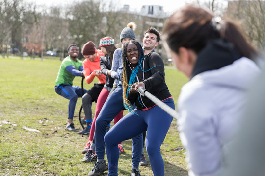 Determined team pulling rope in tug-of-war in park