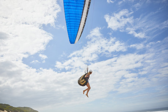 Female paraglider paragliding against sunny blue sky