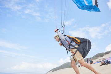 Male paraglider running with parachute on beach